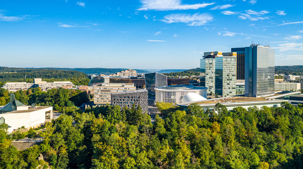Vue aérienne du quartier moderne de Luxembourg-Kirchberg, avec ses gratte-ciels, le Philharmonie Luxembourg et des espaces verts en premier plan.