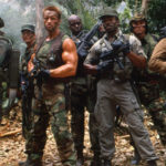 Équipe de soldats en tenue de combat dans une jungle dense, avec Arnold Schwarzenegger au centre, tenant une arme et entouré de ses coéquipiers armés.