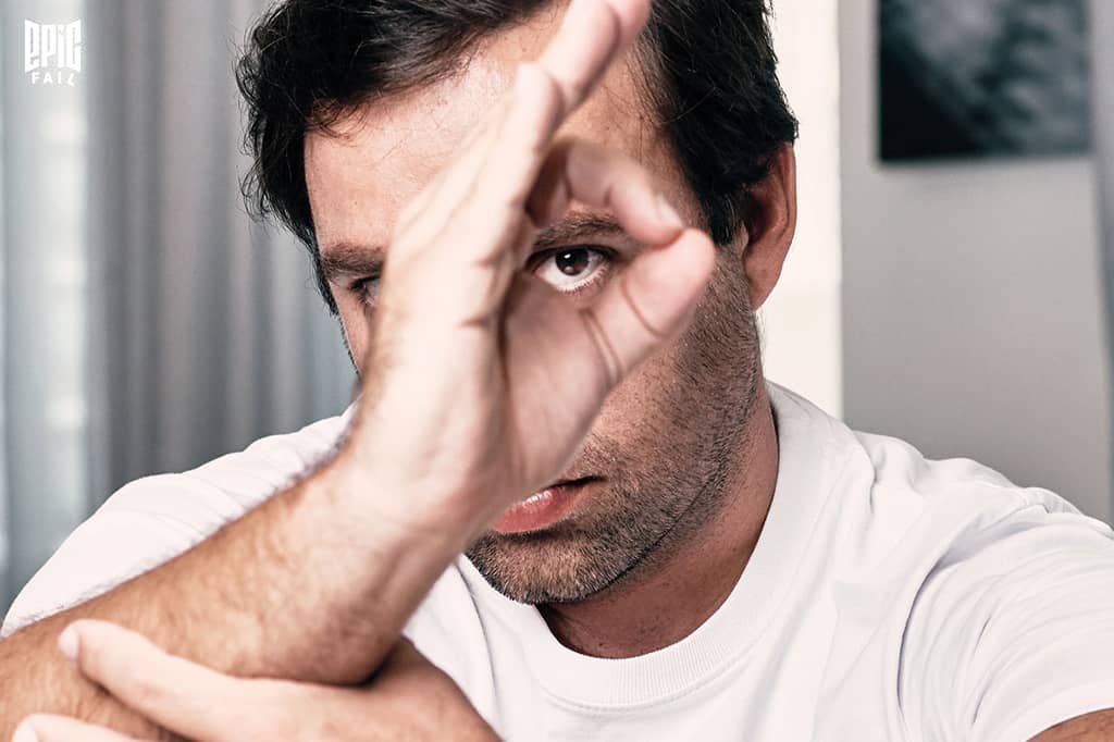 Vincent Faudemer en t-shirt blanc, fixant l’objectif à travers un geste de la main en cercle formant un œil, avec un regard intense. Logo Epic Fail en haut à gauche.